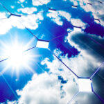 pannelli solari su cui si riflette i cielo azzurro con nuvole e sole